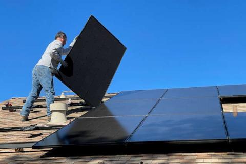 A man installing solar panels on a roof.